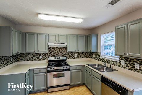 A kitchen with a stove, sink, and cabinets.