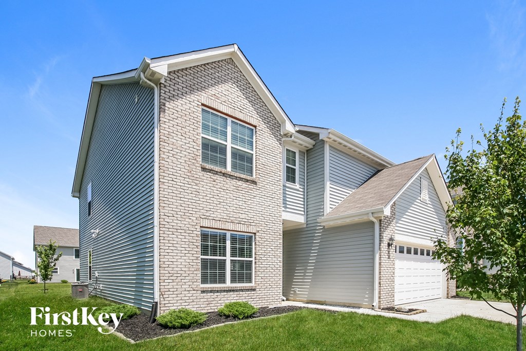 a blue and white brick house with a grassy yard