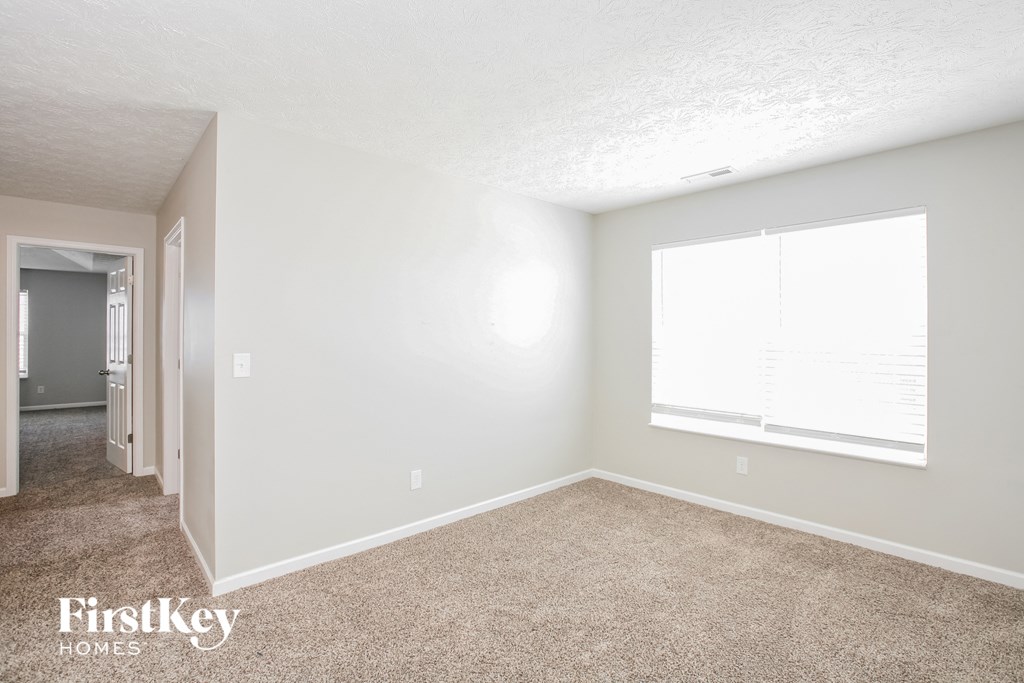 a bedroom with carpet and a large window
