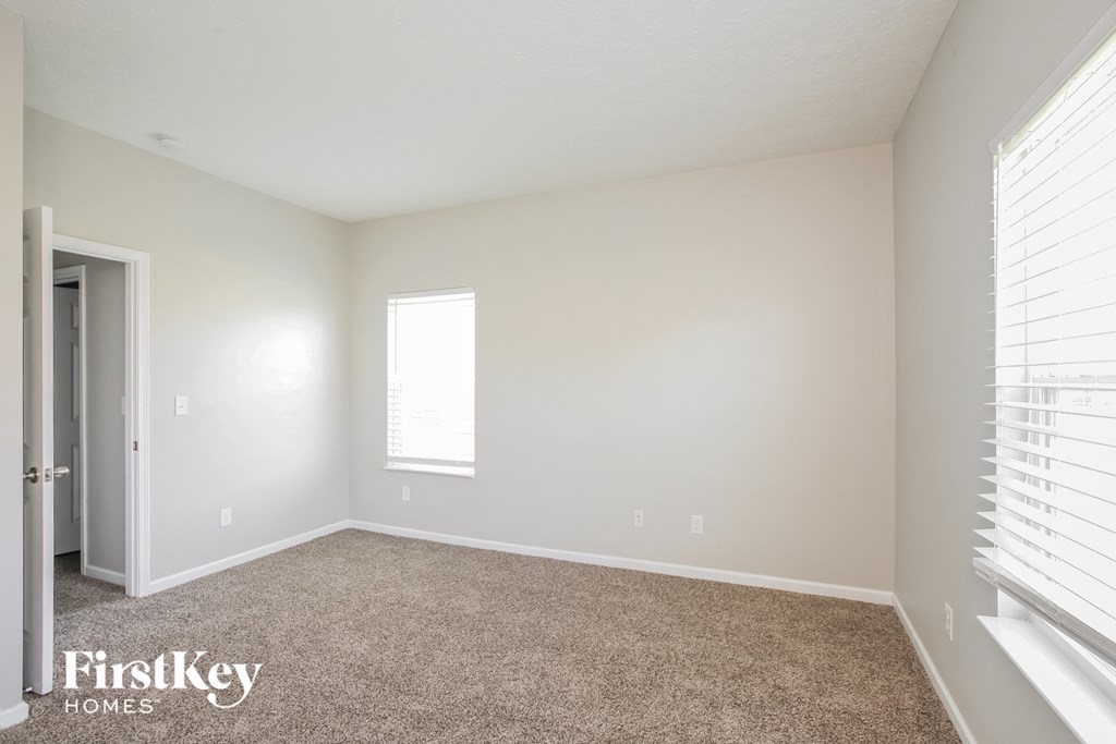 a bedroom with white walls and carpet and a window