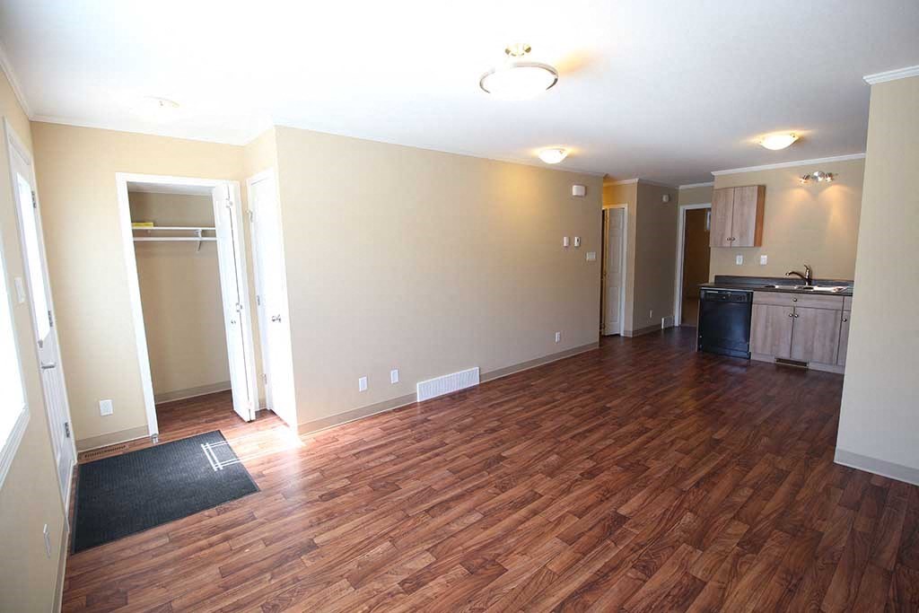 an empty living room and kitchen with wood flooring