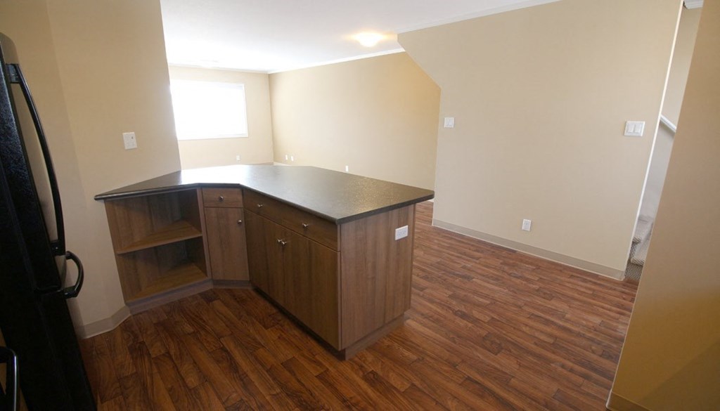 an empty kitchen with wooden floors and a counter top