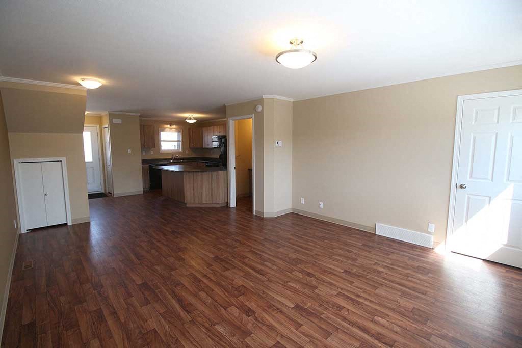 an empty living room and kitchen with a wood floor