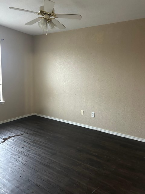 A room with a ceiling fan and wooden flooring.