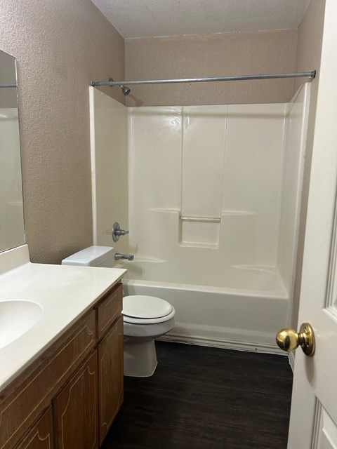 A white bathroom with a toilet, sink, and shower.