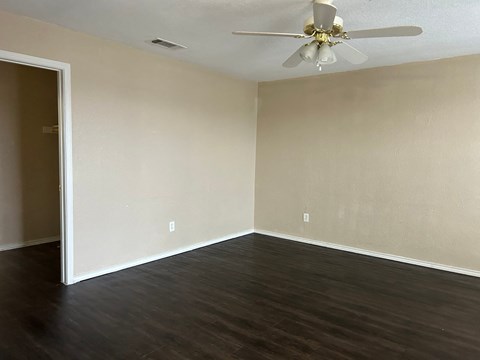 Empty room with a ceiling fan and dark wood flooring.
