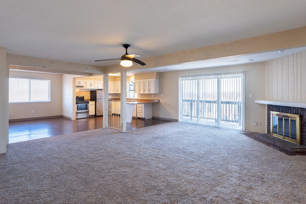 an empty living room with a fireplace and a ceiling fan