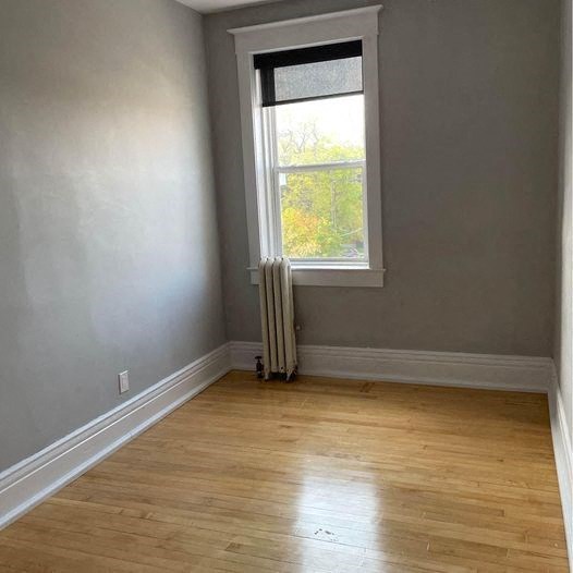 an empty room with a window and wooden floors