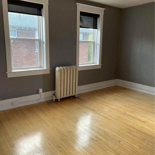 an empty room with a radiator and two windows