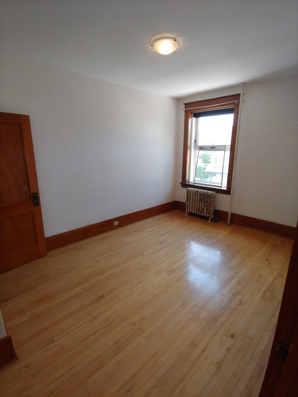 an empty living room with wooden floors and a window
