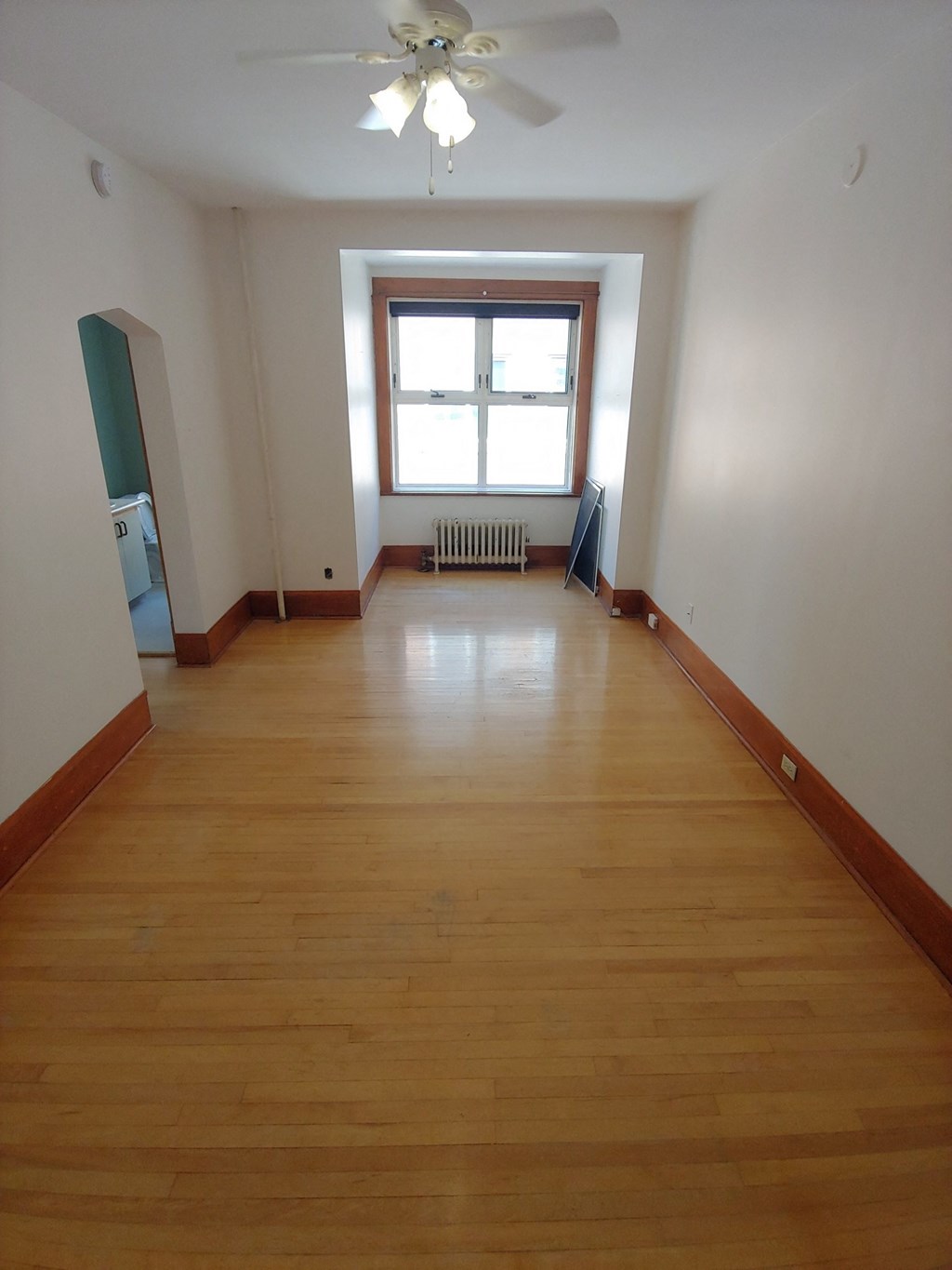 a room with wooden floors and a window and a ceiling fan