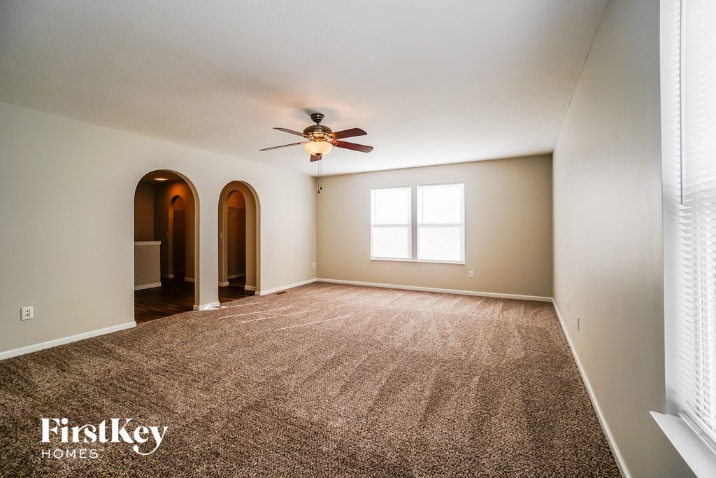an empty living room with a ceiling fan and a carpet