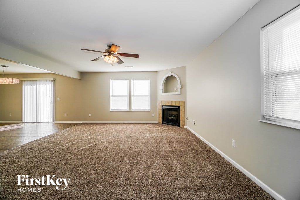 an empty living room with a ceiling fan and a fireplace