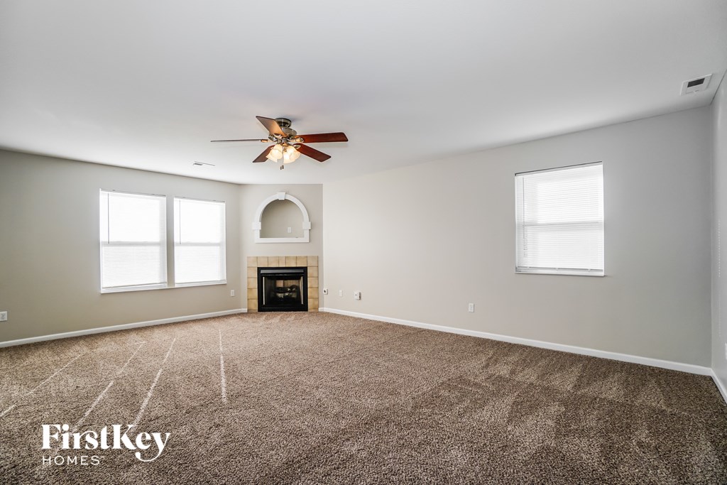 an empty living room with a ceiling fan and a fireplace