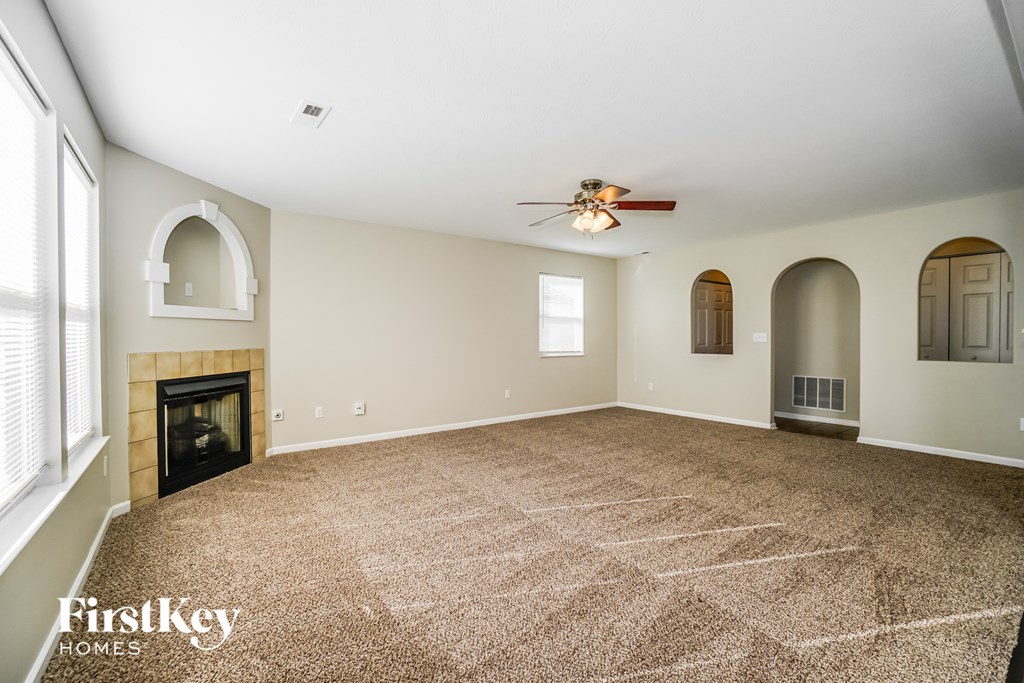 an empty living room with a fireplace and a ceiling fan