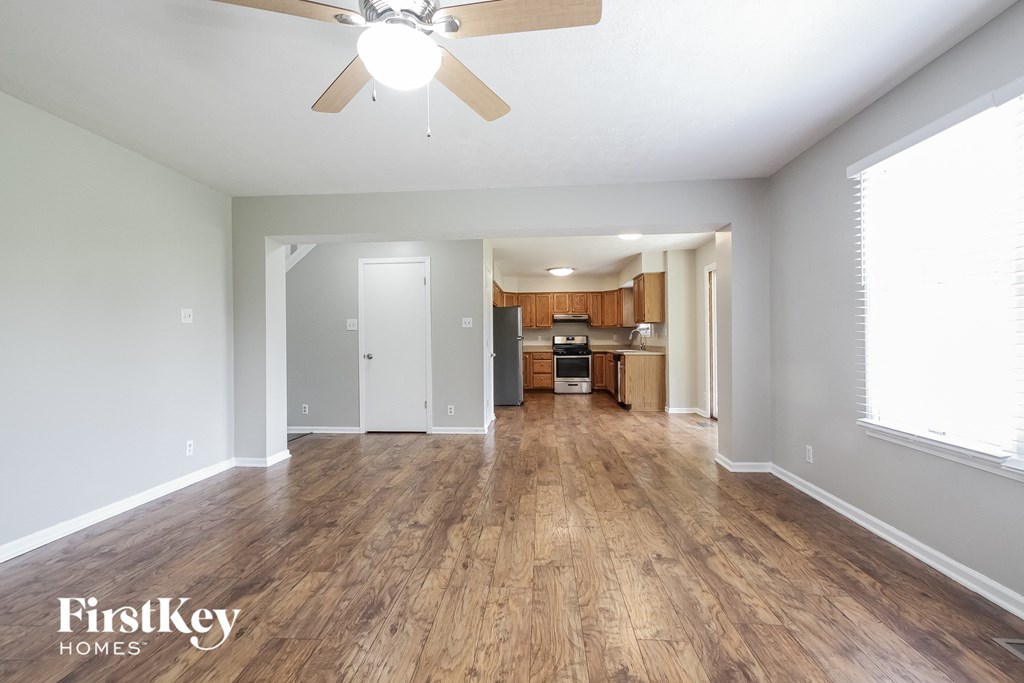 a living room and kitchen with wood flooring and a ceiling fan