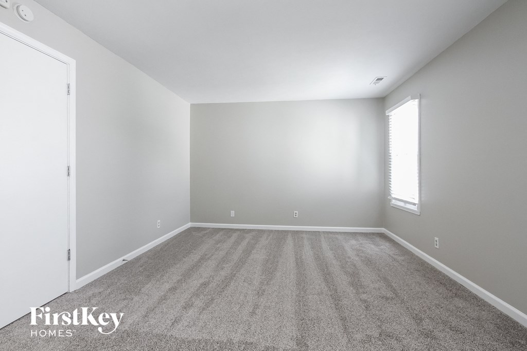 a large empty room with carpet and a window