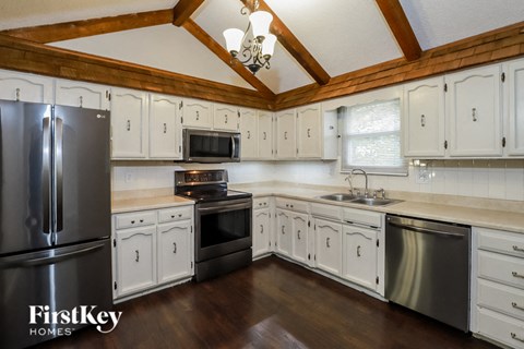 A kitchen with wooden cabinets and a stainless steel refrigerator.