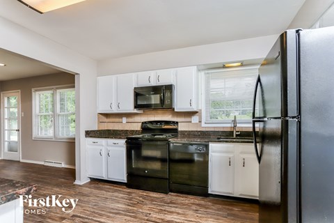 A kitchen with a black fridge and stove top oven.