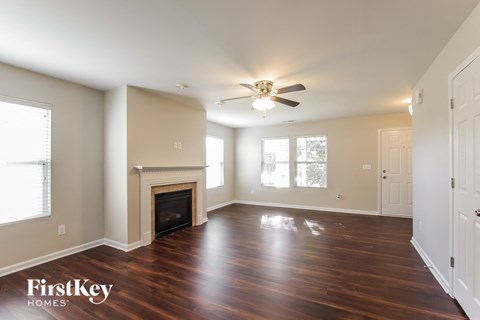 A spacious room with a fireplace and wooden floors.