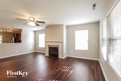 A spacious living room with wood flooring and a fireplace.