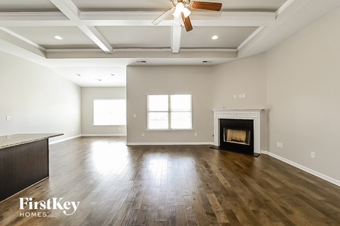 A spacious living room with a fireplace and a ceiling fan.