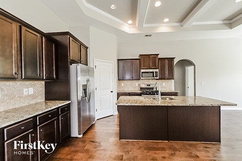 A kitchen with dark brown cabinets and a granite countertop.