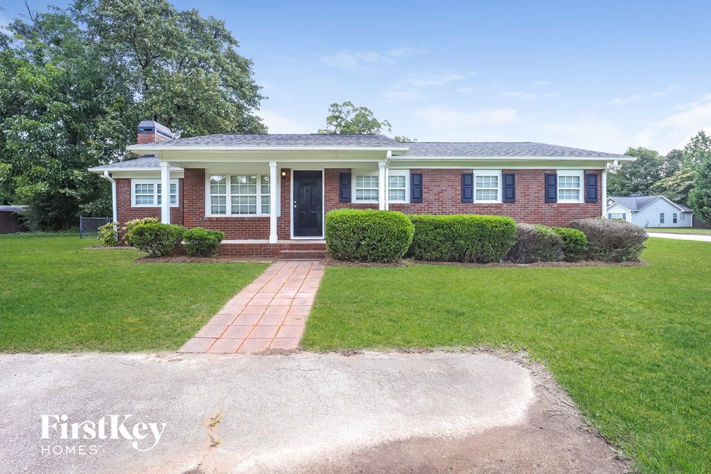 a brick house with a lawn and a sidewalk in front of it