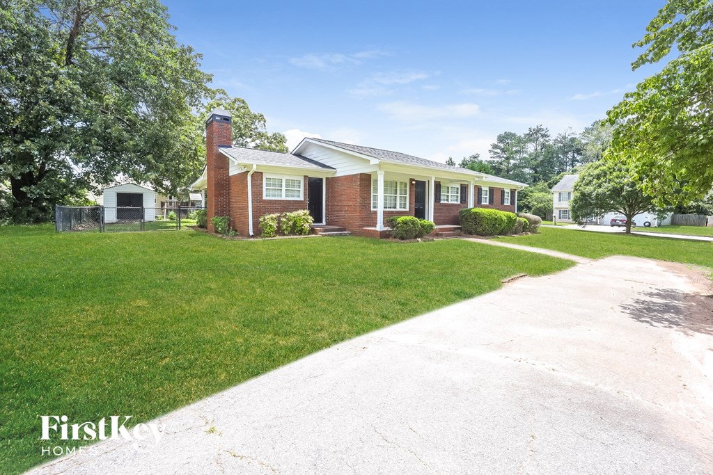 a small brick house with a yard and a white driveway