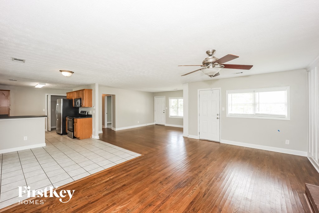 an empty living room with wood floors and a ceiling fan
