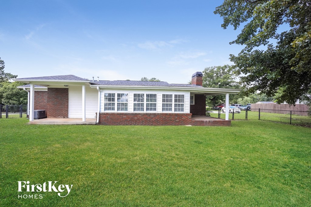 a small brick house with a yard and a fence