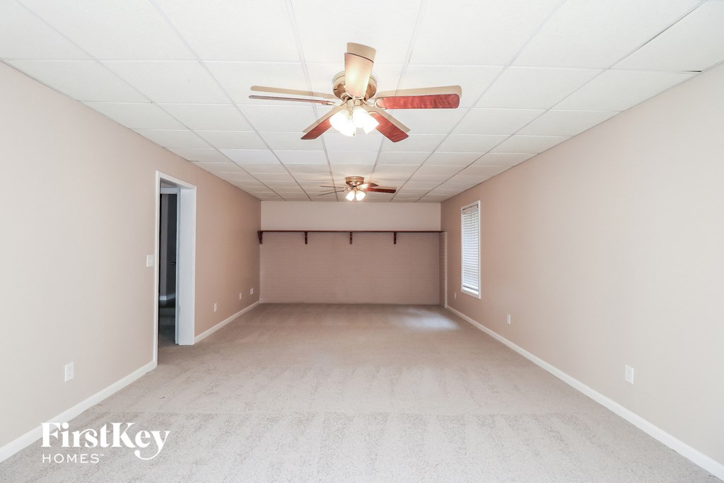 a empty living room with a ceiling fan and a white carpet