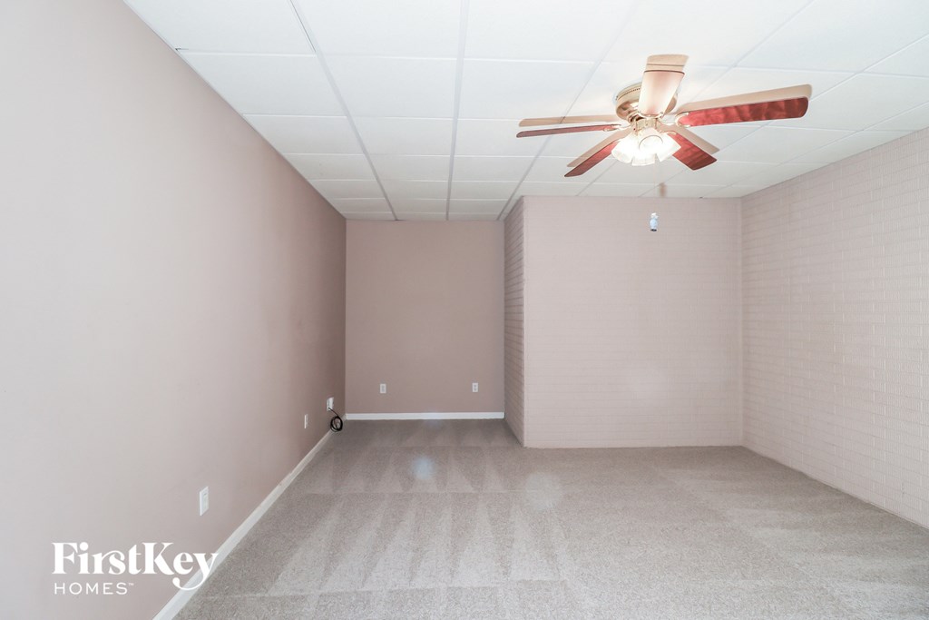 a empty room with a ceiling fan and a brick wall