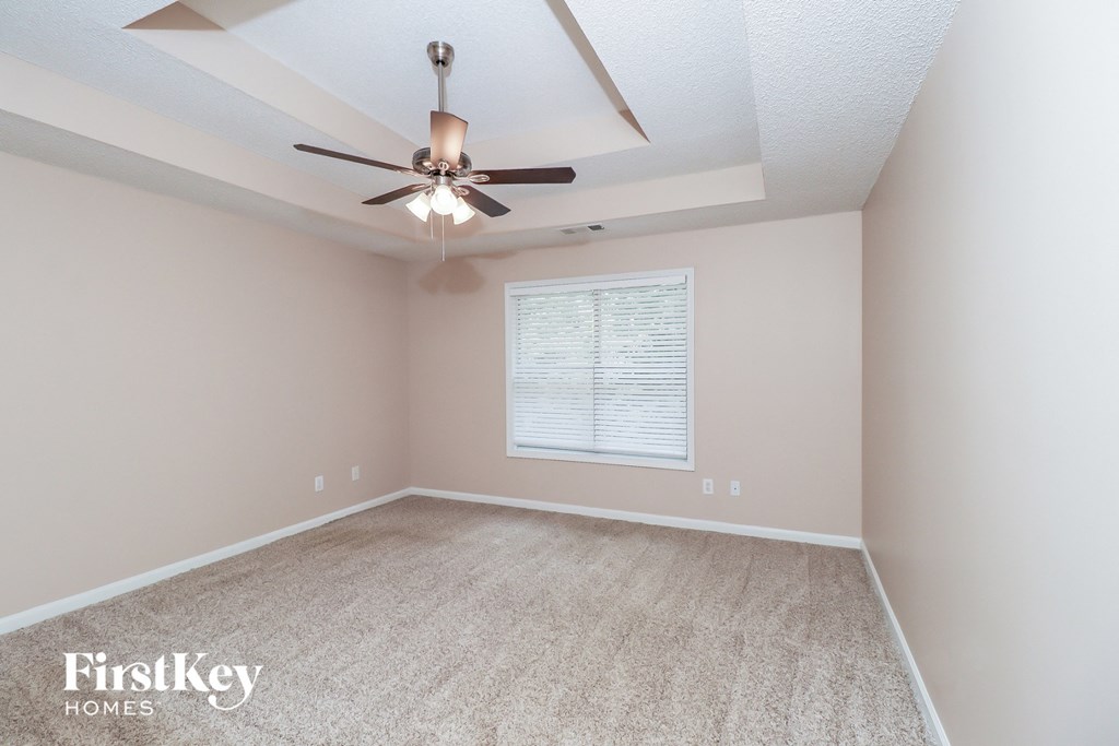 an empty room with a ceiling fan and a window