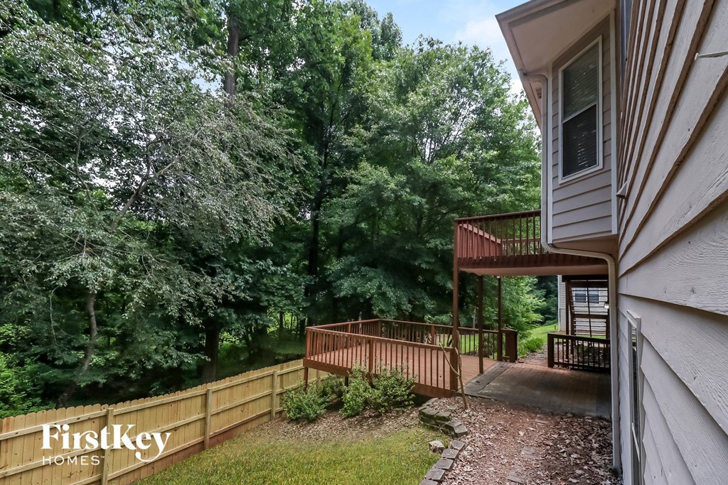 a backyard with trees and a wooden fence and a deck
