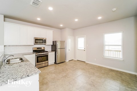A kitchen with white cabinets and a marble countertop.