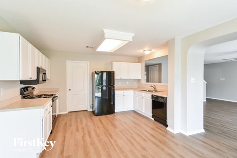 A kitchen with white cabinets and a black fridge.