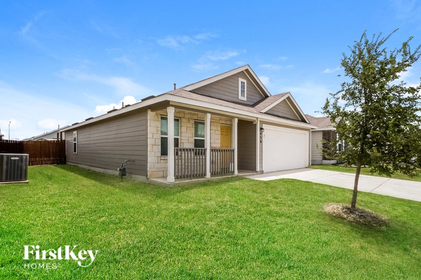 a small brown house with a yard and a white garage