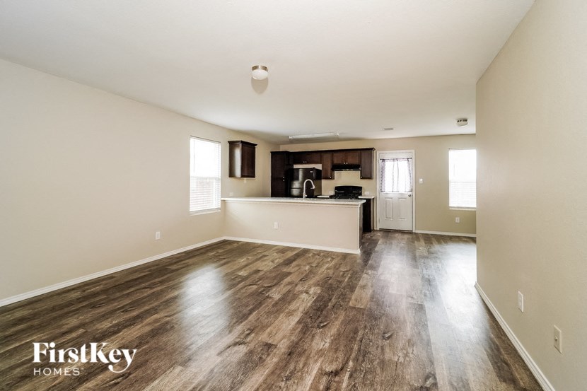 an empty living room and kitchen with wood flooring