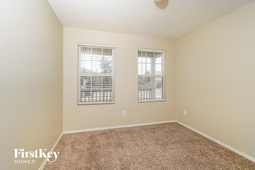 a spacious room with carpet and two windows