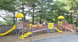 a playground with yellow and blue equipment and people playing on it