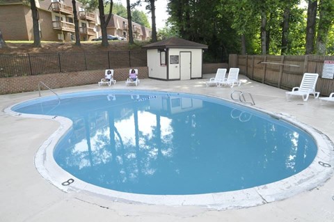 A small pool with a white fence and a brown building in the background.