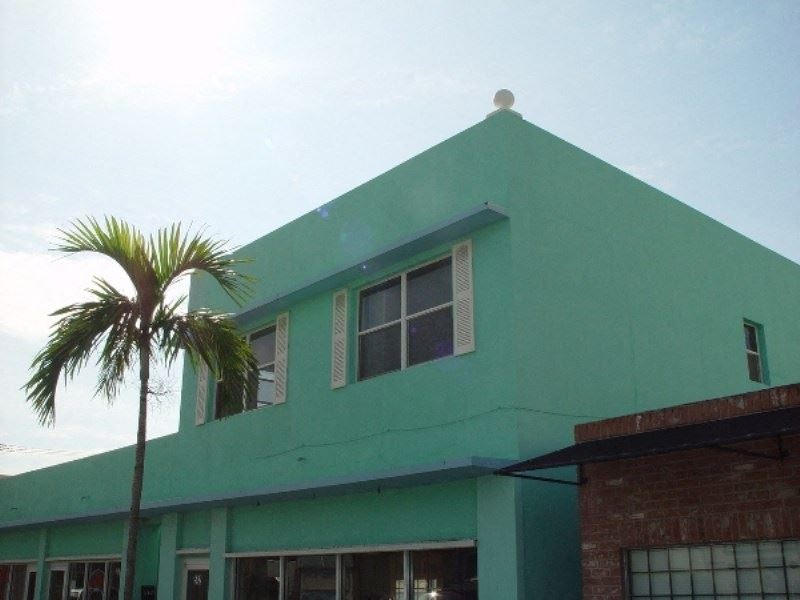 a green building with a palm tree in front of it