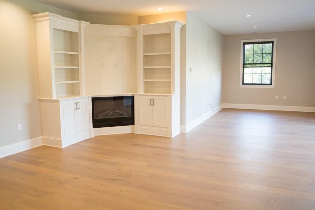 an empty living room with a fireplace and white shelves