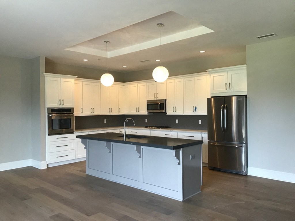 a kitchen with white cabinets and a black counter top