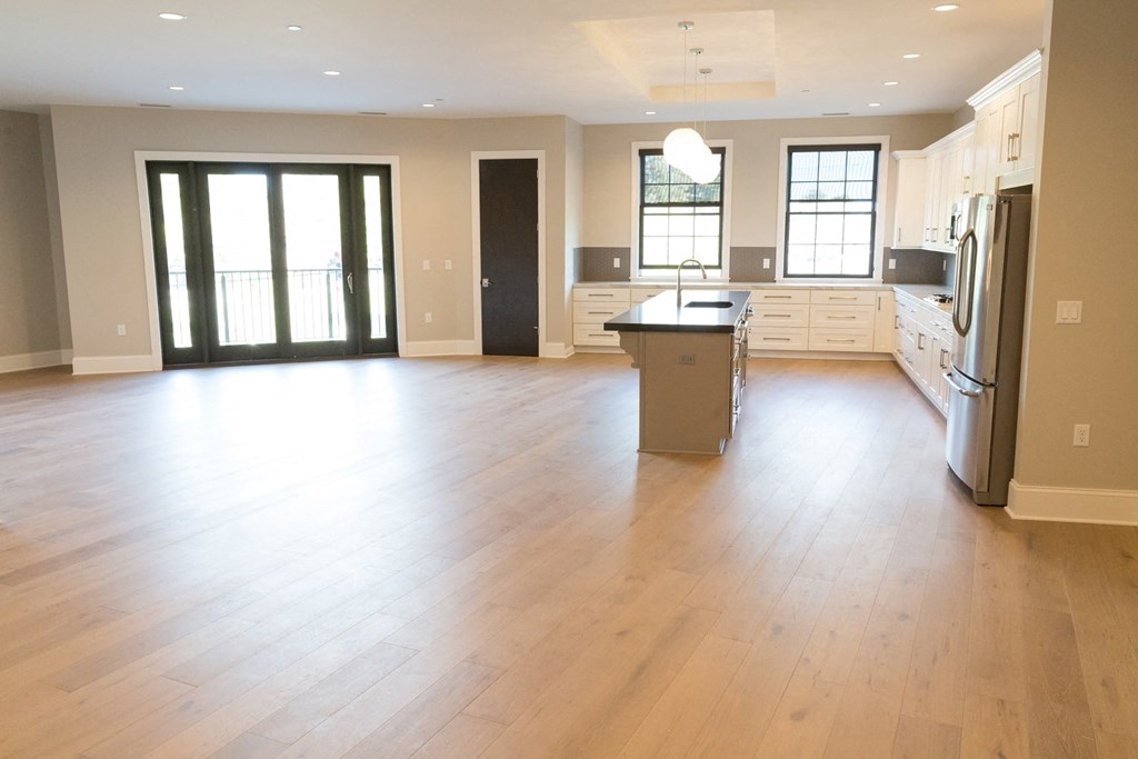 an open kitchen and living room with wood flooring and a center island
