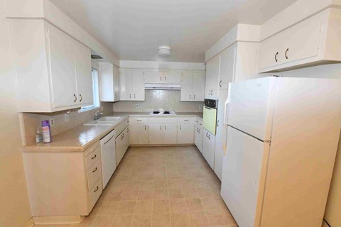A kitchen with white cabinets and appliances.