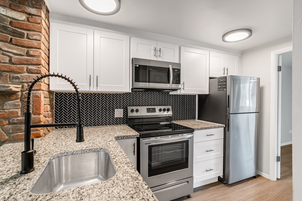 A kitchen with a brick wall and a stainless steel refrigerator.