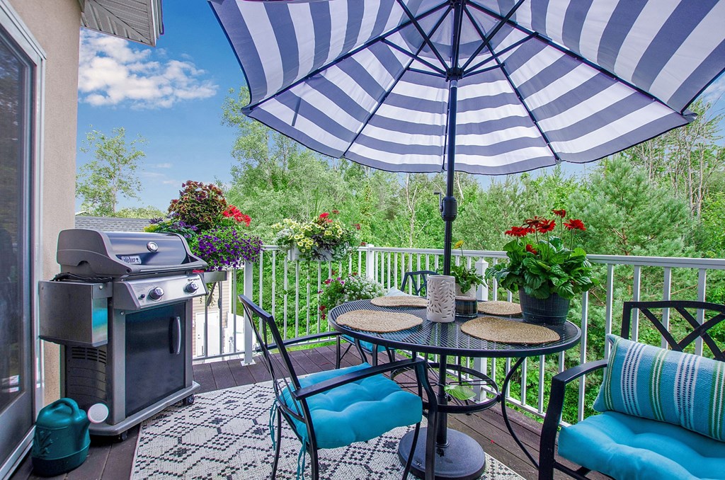 a patio with an umbrella and a grill