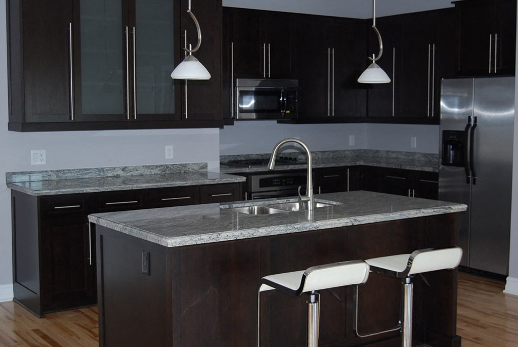 a kitchen with a marble counter top and black cabinets